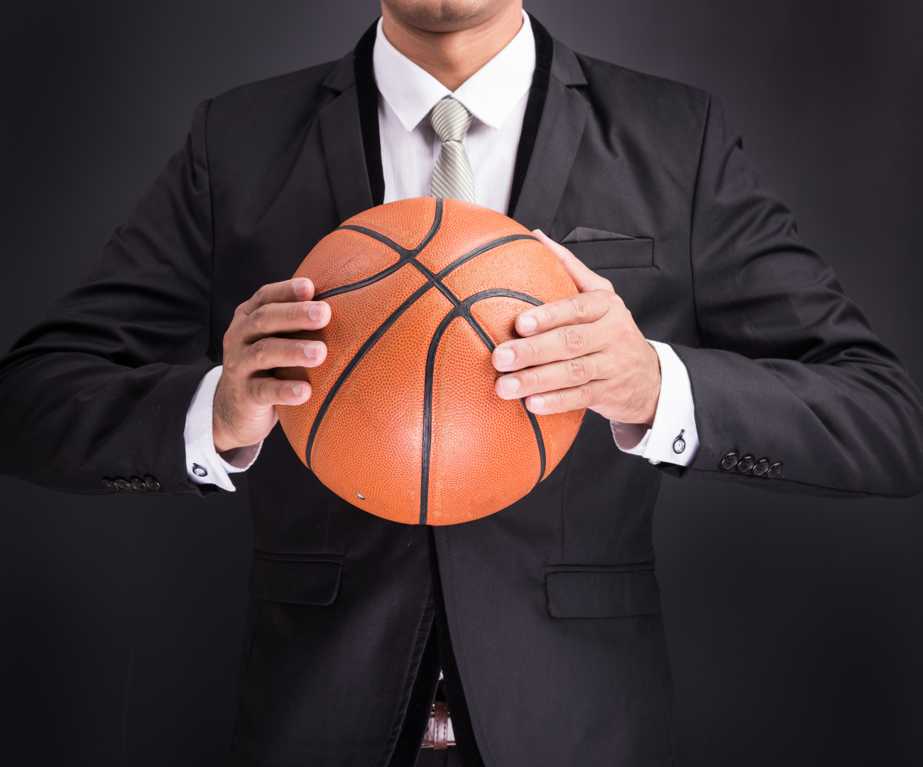 man holding a basketball and wearing a black business suit