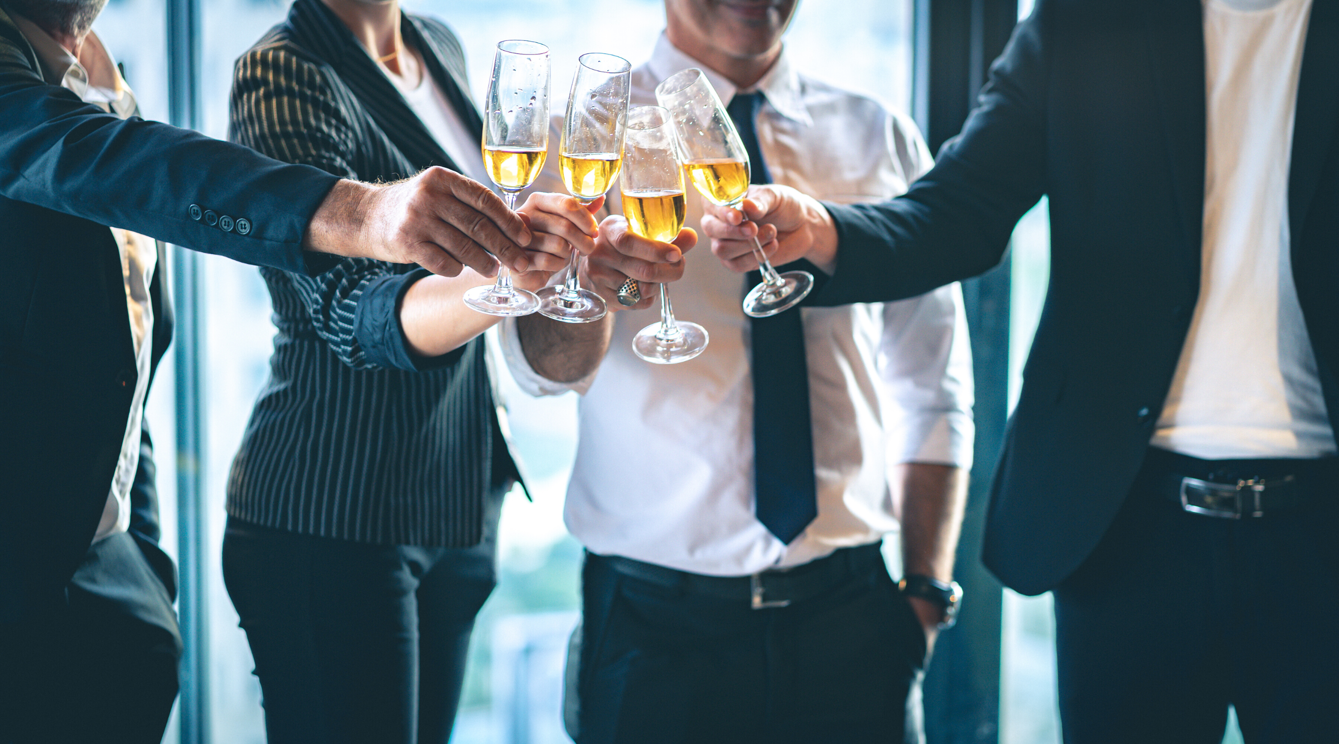 four people in business dress toasting with champagne glasses
